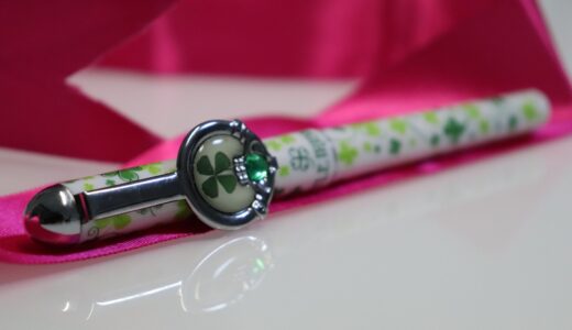 pen, lucky charm, four leaf clover, clover pen, decorative pen, green clover, pink ribbon, writing instrument, elegant gift, good luck, irish symbol, stationery, charm pen, emerald detail, shiny surface, creative gift, cute accessory, gift idea, writing, personal touch, festive decor, stylish pen, desktop item, writing tools, detailed closeup